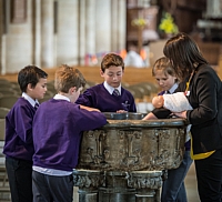 Children watching a baby doll being "baptized" at the Cathedral font